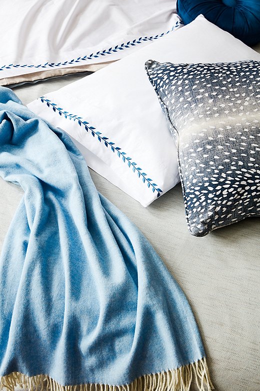 An animal-print pillow provides an unexpected pop among the more-traditional bedding. Shown above: Corbin Spa Duvet Cover, Herringbone Throw in Blue Denim, Meredith Sheet Set in Hamptons Blue, Eileen Round Pillow in Indigo, and Doeskin Pillow in Indigo/White.
